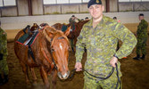 Cpl Hall standing and looking proud after receiving his spurs Senator tacked up with one of the new steel arch saddles
