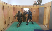 Cpl Gray defends himself from two CQC Instructors in the kill house as his course mates cheer him on. Photo: Cpl Sawyer
